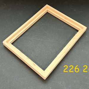 May include: A rectangular, unfinished wooden frame. The frame is made of light-colored wood and has a double-layered design. The number "226 26" is printed in yellow on the bottom right corner of the frame.