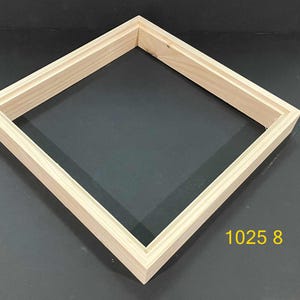 May include: A square, unfinished light-colored wooden frame with a stepped, tiered profile edge. The frame is positioned at an angle, and the number 1025 8 is printed in yellow text in the lower right corner of the frame's interior space.