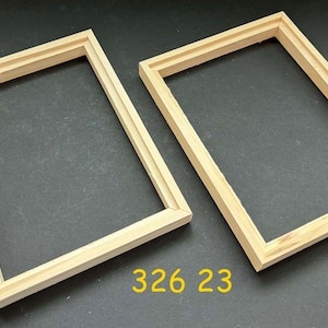 May include: Two unfinished, rectangular wooden frames with a light brown color. The frames are empty and have a grooved design. The number "326 23" is printed in yellow at the bottom.