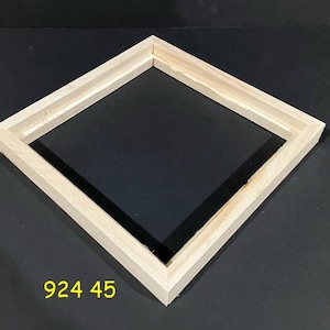May include: A square wooden frame, constructed from light-colored wood, is positioned diagonally. The frame has a recessed inner edge. The number "924 45" is printed in yellow at the bottom. The frame is set against a dark background.