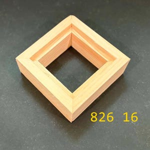 May include: A square, light-colored wooden frame with a mitered corner construction and a recessed inner edge. The frame has a natural wood grain texture and is positioned at an angle. The yellow text 826 16 is visible near the bottom right corner.