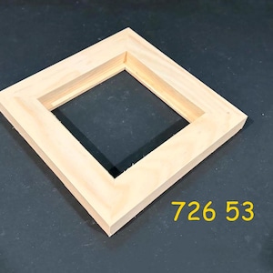 May include: A square, unfinished light-colored wooden frame with mitered corners and a flat profile. The frame has a hollow center and is positioned at an angle. The yellow text 726 53 is printed in the lower right corner of the image.