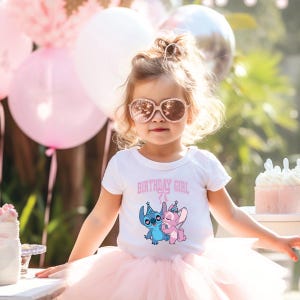 May include: A young child wearing a white t-shirt with the text "BIRTHDAY GIRL" and a cartoon graphic of Stitch and Angel. The child is also wearing a pink tutu, rose-colored sunglasses, and has a hair accessory. Pink balloons and a cake are in the background.