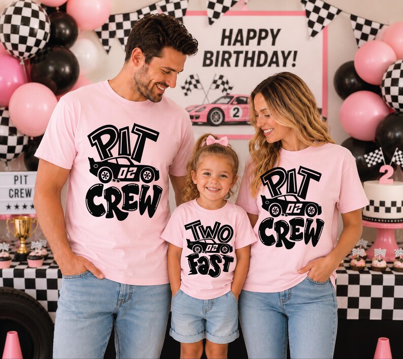 May include: Three light pink t-shirts featuring black graphic prints. Two shirts display the text "PIT CREW" with a race car illustration, while the smaller shirt displays the text "TWO FAST" with a race car illustration.