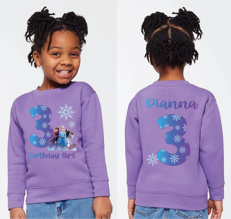 Pode incluir: Um moletom lil&aacute;s com um grande n&uacute;mero 3 e desenhos de flocos de neve, al&eacute;m de um gr&aacute;fico de Frozen. A frente diz "Birthday Girl". A parte de tr&aacute;s do moletom tem o nome "Dianna" e o n&uacute;mero 3.