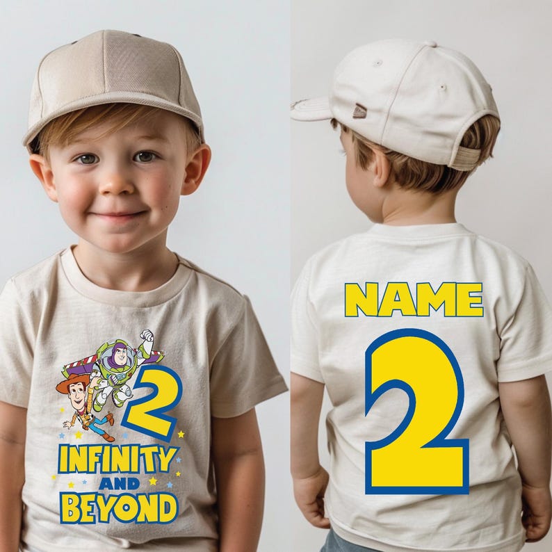 Op de afbeelding: Een beige T-shirt met een cartoon afbeelding van Woody en Buzz Lightyear uit Toy Story. Het shirt heeft het nummer "2" en de tekst "Infinity and Beyond". De achterkant van het shirt heeft het nummer "2" en de tekst "NAME".