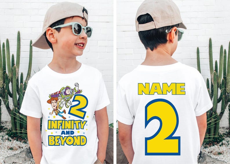 Op de afbeelding: Wit T-shirt met een cartoon afbeelding van Buzz Lightyear en Woody uit Toy Story. Het shirt heeft de tekst "Infinity and Beyond" en het nummer "2" op de voorkant. De achterkant van het shirt heeft de tekst "NAME" en het nummer "2" in geel.