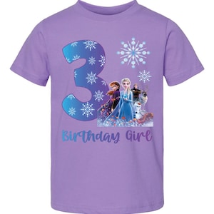 Pode incluir: Uma camiseta lil&aacute;s de manga curta com um gr&aacute;fico do n&uacute;mero 3, flocos de neve e personagens do filme Frozen. O texto "Birthday Girl" est&aacute; abaixo do gr&aacute;fico.