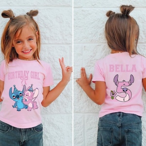 May include: A pink t-shirt with the text "BIRTHDAY GIRL" and a cartoon image of Stitch and Angel. The back of the shirt has the name "BELLA" and a number 5 with a flower. The girl is wearing blue scrunchies.