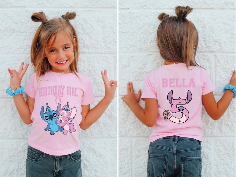 May include: A pink t-shirt with the text "BIRTHDAY GIRL" and a cartoon image of Stitch and Angel. The back of the shirt has the name "BELLA" and a number 5 with a flower. The girl is wearing blue scrunchies.