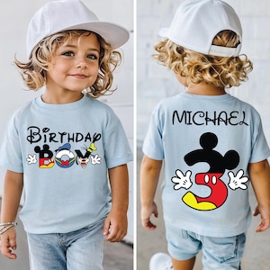 May include: Pale blue t-shirt featuring "Birthday Boy" with Mickey Mouse, Donald Duck, and Goofy characters. The back displays "MICHAEL" and a Mickey Mouse graphic with the number "3".
