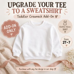 Może przedstawiać: Gładka biała bluza z okrągłym dekoltem dla małych dzieci. Tekst na obrazku brzmi: UPGRADE YOUR TEE TO A SWEATSHIRT, Toddler Crewneck Add-On, ADD-ON ONLY, Rabbit Skins 3317, Sizes 2T-7 oraz Purchase with any tee design in our shop.
