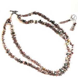 May include: A multi-strand necklace and matching earrings made with small, irregular, multi-colored stones. The stones are a mix of brown, red, green, and white.