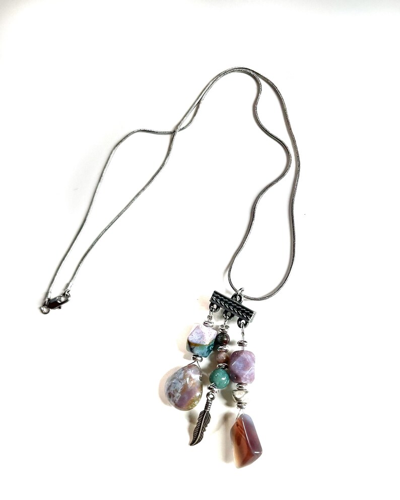 May include: A silver chain necklace with a pendant featuring a cluster of colorful agate stones, a silver feather charm, and silver beads.