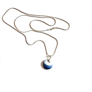 May include: A silver chain necklace with a round blue and white pendant.