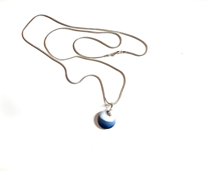 May include: A silver chain necklace with a round blue and white pendant.