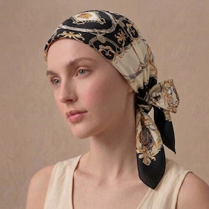 Peut inclure: Un foulard en soie avec un motif baroque noir, crème et or. Le foulard est noué à l'arrière de la tête, avec les extrémités pendantes. Le motif présente des détails ornés et une esthétique classique.