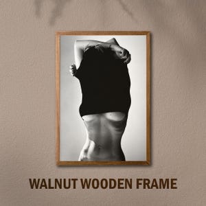 May include: Black and white photo of a person in a black shirt, framed in a walnut wood frame.