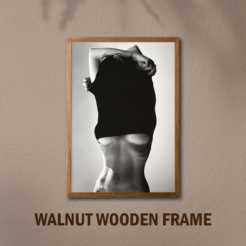 May include: Black and white photo of a person in a black shirt, framed in a walnut wood frame.