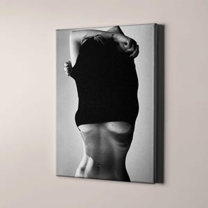 May include: A black and white photo of a person with their shirt pulled up, revealing their torso.