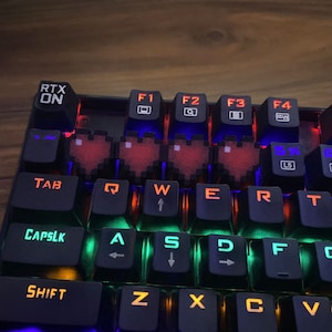 May include: A black mechanical keyboard with red, green, and blue LED lights. The keyboard has a row of function keys (F1-F4) and a row of keys with the letters QWERTYUIOP. The keyboard also has a row of keys with the letters ASDFGHJKL. The keyboard has a row of keys with the letters ZXCVBNM. The keyboard has a row of keys with the letters 1234567890. The keyboard has a row of keys with the symbols ~!@#$%^&*()_+=-`[]";',./<>?:"{}|