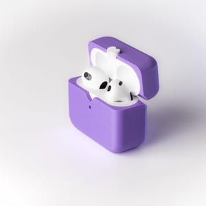 Pu&ograve; includere: Una custodia in silicone viola per auricolari wireless, con il coperchio aperto e gli auricolari all'interno. Gli auricolari sono bianchi e hanno un piccolo microfono su ciascuno.