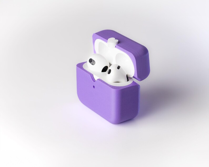 Pu&ograve; includere: Una custodia in silicone viola per auricolari wireless, con il coperchio aperto e gli auricolari all'interno. Gli auricolari sono bianchi e hanno un piccolo microfono su ciascuno.