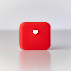 Pu&ograve; includere: Una custodia quadrata rossa con un cuore bianco in cima.