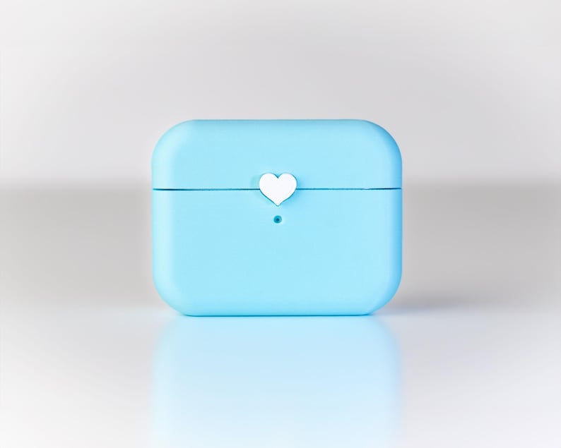 Pu&ograve; includere: Una custodia protettiva di colore azzurro per auricolari wireless con un piccolo dettaglio a forma di cuore bianco nella parte superiore.