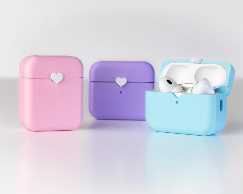Pu&ograve; includere: Tre custodie in silicone per auricolari wireless. Le custodie sono rosa, viola e blu chiaro. La custodia blu chiaro &egrave; aperta e mostra due auricolari bianchi all'interno.