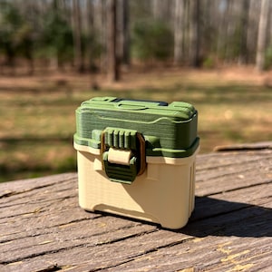 May include: A small, green and white tackle box with a latch and a handle. The box is made of plastic and has a textured surface.