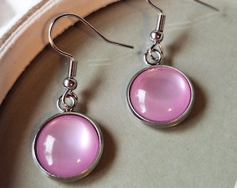 May include: A pair of silver earrings with pink iridescent round cabochon stones.