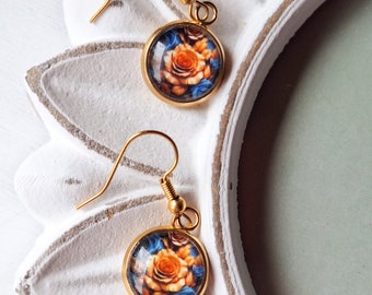 May include: A pair of gold-tone earrings with a round, glass cabochon featuring a floral design. The cabochons are decorated with a pattern of orange and blue roses.