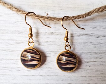 May include: A pair of gold earrings with round, brown and white striped glass cabochons. The earrings have a simple, elegant design.