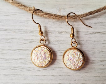 May include: A pair of gold earrings with white glitter round cabochon stones.