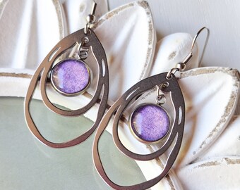 May include: A pair of silver earrings with a purple glass cabochon in each. The earrings are made of two overlapping circles.