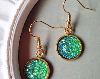 May include: A pair of gold dangle earrings with round green glitter accents.