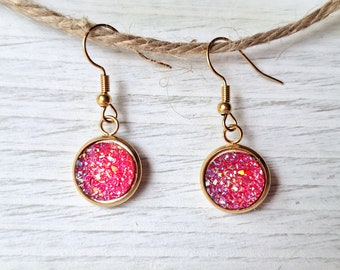 May include: Gold dangle earrings with round pink glitter-filled cabochons.