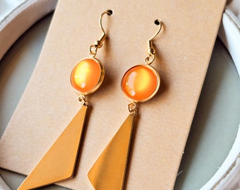 May include: A pair of gold earrings with orange glass cabochons and triangular dangles.