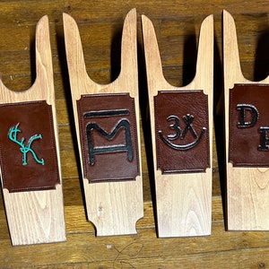 Peut inclure: Quatre tire-bottes en bois avec des patchs en cuir. Les patchs ont des motifs différents, dont un cerf, une lettre M, un 3X et les lettres DP.