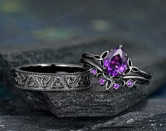 May include: Two black rings. One ring features a band with a Celtic knot design. The other ring has a pear-shaped purple gemstone and smaller purple gemstones. The rings are set on a dark, textured surface.