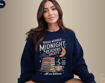 Może przedstawiać: Granatowa bluza z napisem "Proud Member Midnight Readers Society". Projekt zawiera stos książek, półksiężyc i filiżankę herbaty. Na bluzie wydrukowano również frazę "All are Welcome".