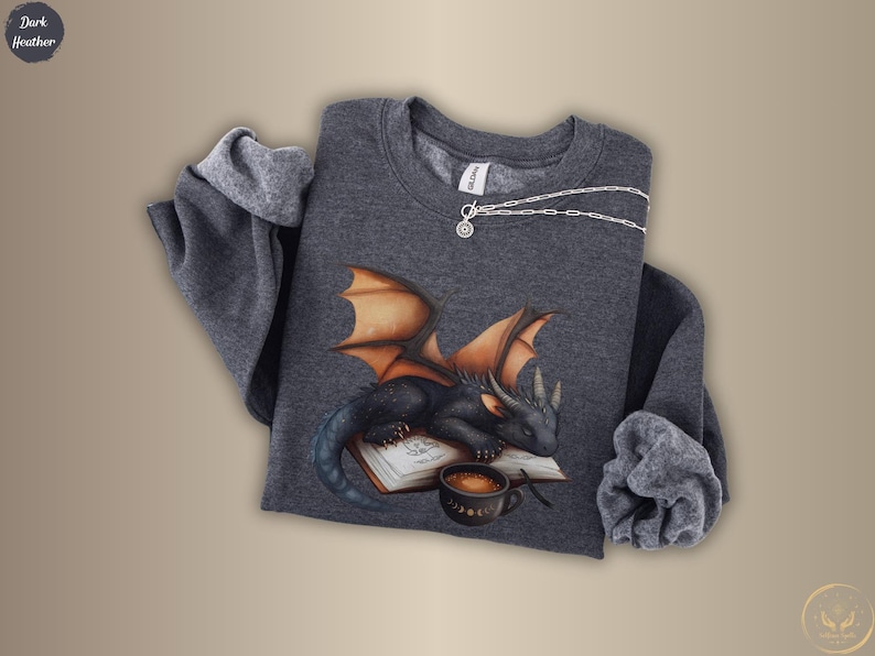 Cozy sweatshirt with cute black dragon sleeping on book on dragonkind with mug of coffee with moon phase pattern. Fourth wing Tairn Andarna dragons bookish booktok bookstagram  fantasy fan reader romantasy coffee lover gift idea soft warm sweater GOT