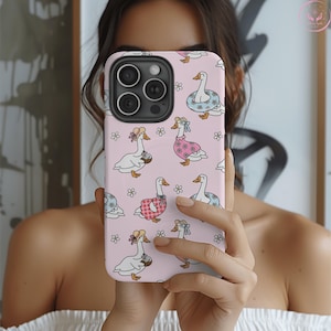 Whimsical summer geese phone case featuring pastel pink background, cottagecore aesthetic, daisies, coquette vibes, floral charm, vintage-inspired design, gingham dresses, daisy lifebuoys, coconut drinks, ribbons, feminine style, nature-inspired art, dreamy pastel colors, aesthetic accessories, playful summer theme, MagSafe compatibility, trendy design, botanical whimsy, English garden feel, charming and delicate vibes, perfect for fashion-forward phone case lovers.