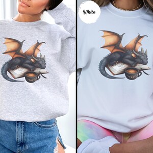 Cozy sweatshirt with cute black dragon sleeping on book on dragonkind with mug of coffee with moon phase pattern. Fourth wing Tairn Andarna dragons bookish booktok bookstagram  fantasy fan reader romantasy coffee lover gift idea soft warm sweater GOT