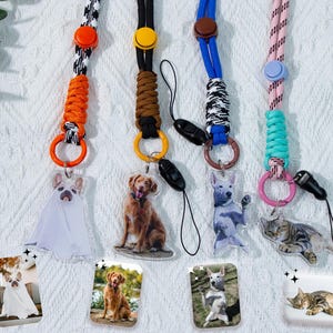 Peut inclure: Cinq lanyards colorés avec des motifs et des breloques différents. Chaque lanyard a un charme en plastique transparent avec une photo d'un chien ou d'un chat. Les breloques sont attachées aux lanyards avec des anneaux métalliques.