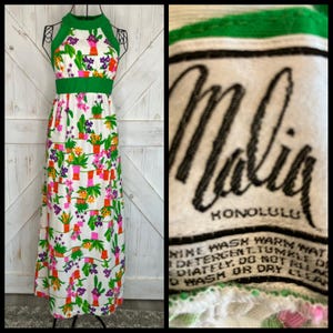 Puede incluir: Un vestido largo vintage con cuello halter, con un fondo blanco y un estampado floral colorido. El vestido presenta detalles verdes en el cuello, la cintura y los bordes. El diseño floral incluye flores naranjas, rosas y moradas en macetas rojas. La etiqueta dice "Malia Honolulu".