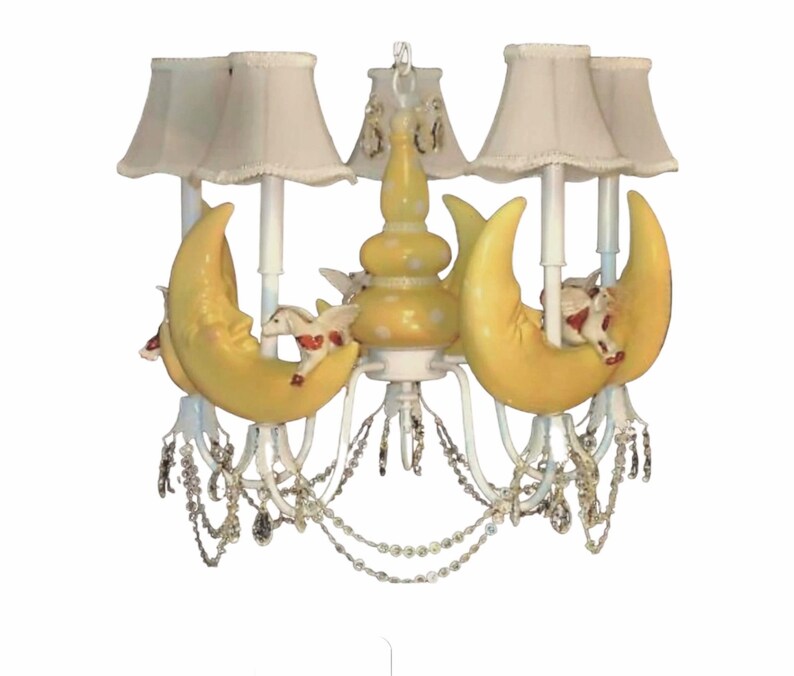 May include: A white chandelier with yellow crescent moons and white horses. The chandelier has crystal-like beads hanging from it.