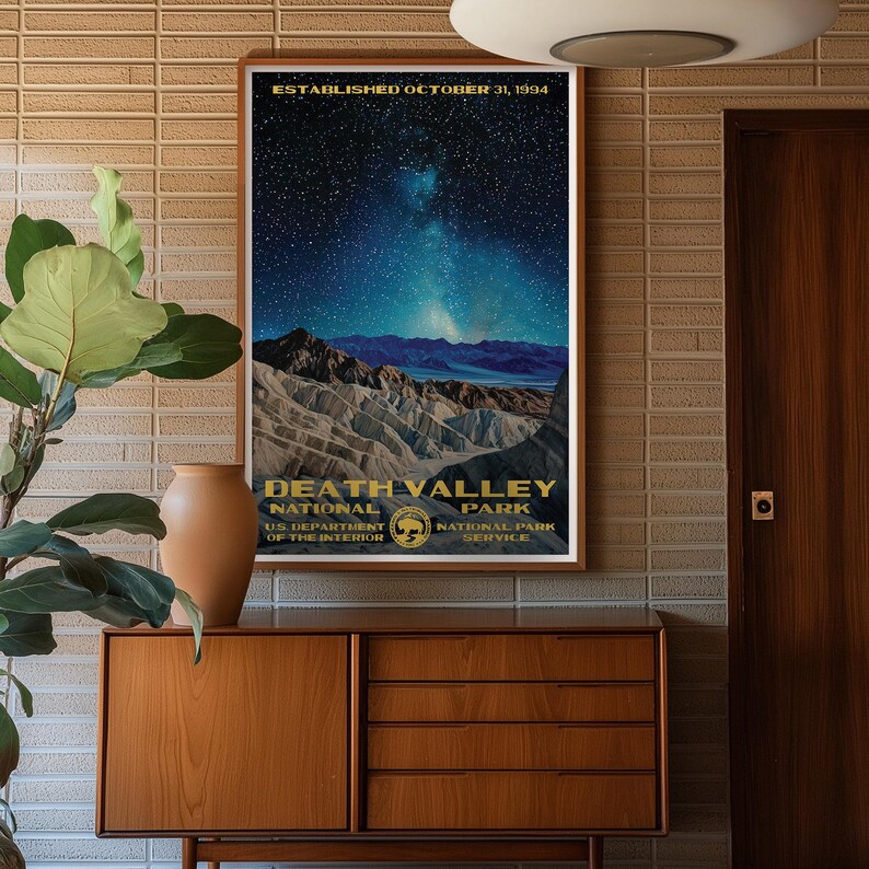 K&ouml;nnte beinhalten: Ein Vintage-Poster mit einem sternenklaren Nachthimmel &uuml;ber einem Gebirge. Das Poster tr&auml;gt die Aufschrift "Death Valley National Park" mit dem Text "Established October 31, 1994" oben. Das Poster ist gerahmt und h&auml;ngt an einer Wand.