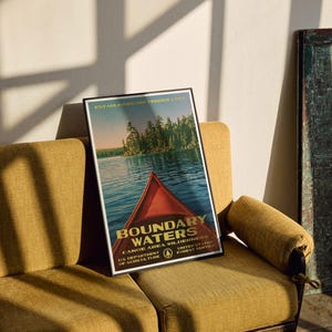 Peut inclure: Une affiche encadr&eacute;e montrant un cano&euml; rouge sur une eau bleue avec une &icirc;le bois&eacute;e en arri&egrave;re-plan. Le texte indique BOUNDARY WATERS CANOE AREA WILDERNESS, ESTABLISHED SEPTEMBER 3, 1964, U.S. DEPARTMENT OF AGRICULTURE, UNITED STATES FOREST SERVICE.
